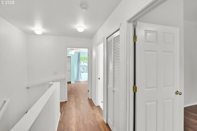 hall featuring wood finished floors, an upstairs landing, and baseboards