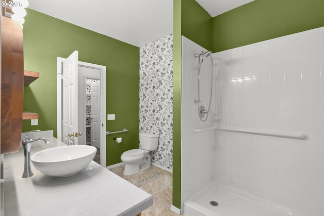 full bathroom featuring a sink, tiled shower, toilet, and baseboards