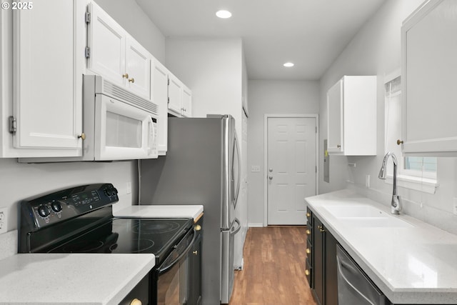 kitchen with black electric range, white microwave, a sink, stainless steel dishwasher, and wood finished floors