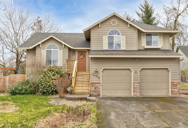 split level home featuring brick siding, a shingled roof, fence, concrete driveway, and a garage