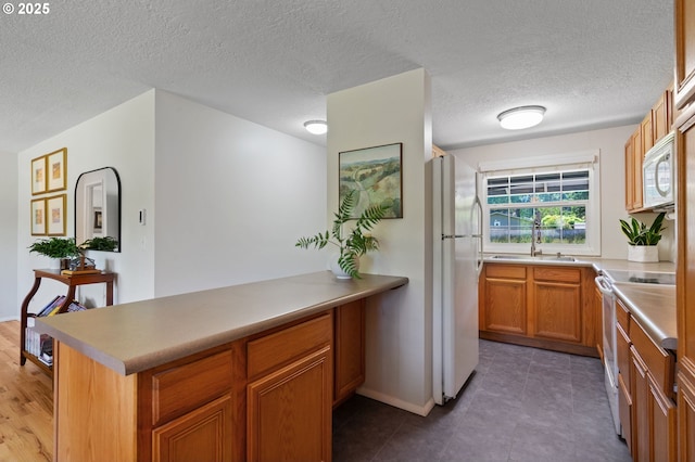 18344 Terry Ave, Lake Oswego, OR 97035 - kitchen with white appliances, a peninsula, a sink, brown cabinetry, and light countertops