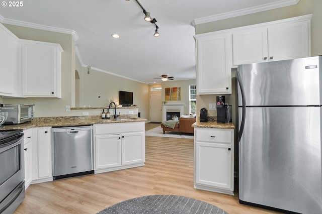 595 Springtree Ln, West Linn, OR 97068 - kitchen with stainless steel appliances, a sink, a ceiling fan, a fireplace, and white cabinetry