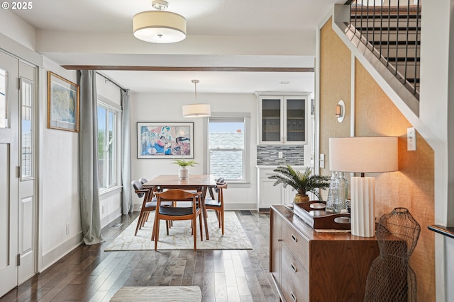 dining room featuring dark wood-type flooring, stairway, and baseboards