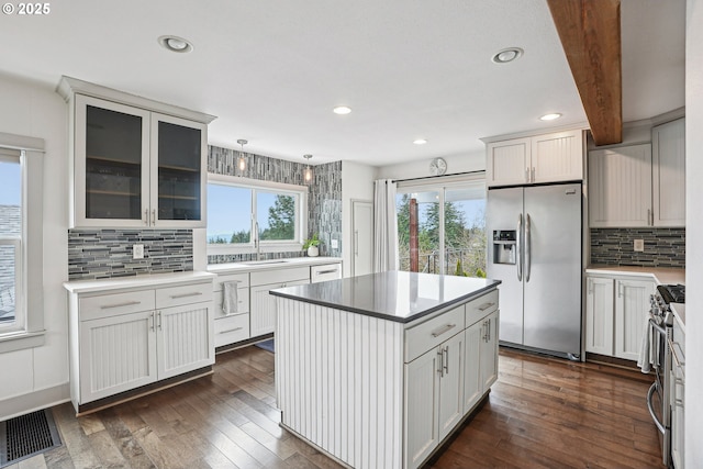 kitchen with stainless steel appliances, dark wood finished floors, visible vents, and decorative backsplash