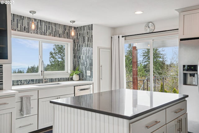 kitchen featuring stainless steel appliances, a sink, a center island, and pendant lighting