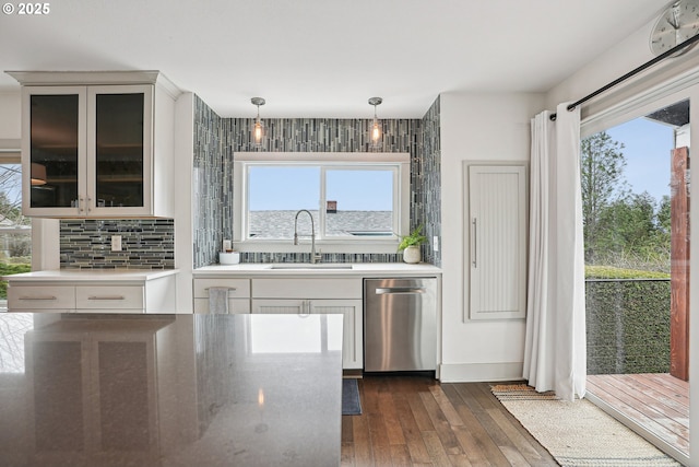 kitchen featuring tasteful backsplash, dishwasher, dark wood-style floors, glass insert cabinets, and a sink