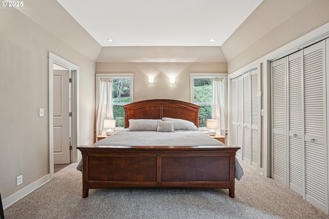 bedroom with recessed lighting, vaulted ceiling, carpet, and two closets