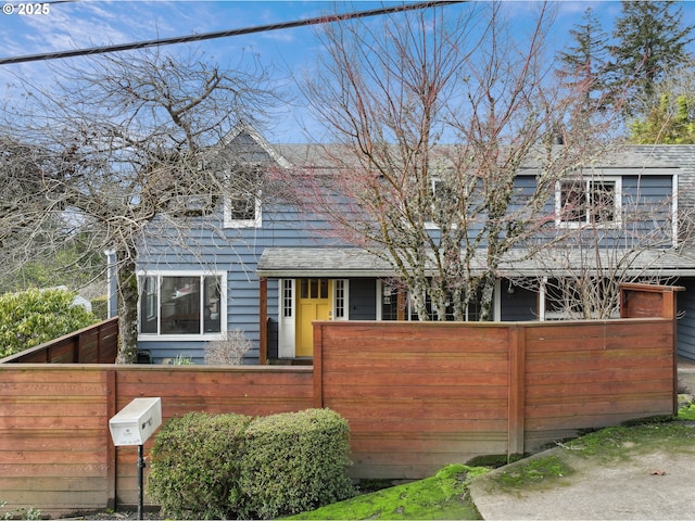 view of front facade featuring a fenced front yard and roof with shingles