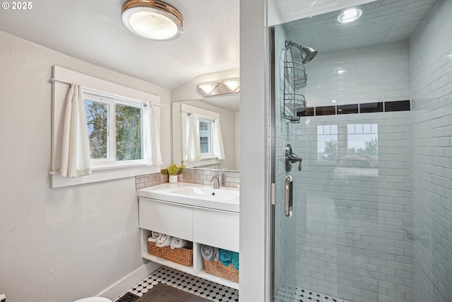 full bath featuring a stall shower, baseboards, vaulted ceiling, and vanity