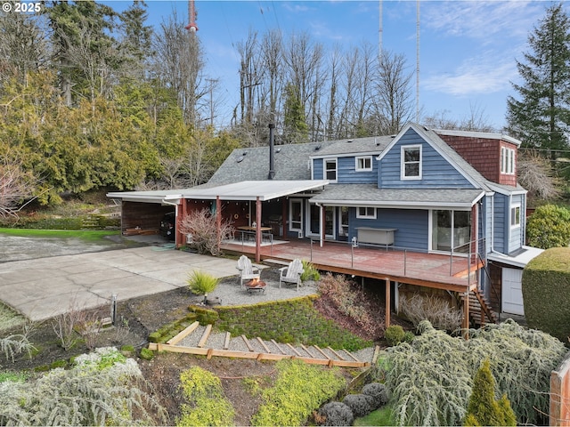 back of property with stairway, a fire pit, a deck, and roof with shingles