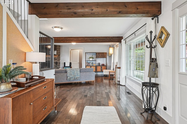 living room featuring dark wood-style floors, visible vents, beamed ceiling, and baseboards