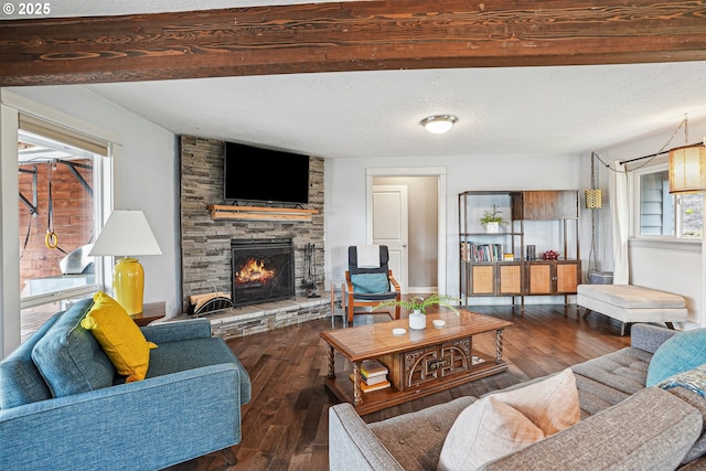 living area featuring a textured ceiling, a stone fireplace, wood finished floors, and beam ceiling