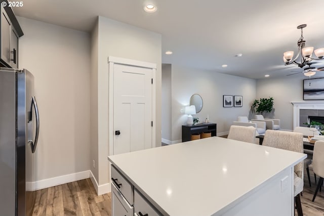 kitchen featuring a center island, stainless steel fridge with ice dispenser, hanging light fixtures, light hardwood / wood-style flooring, and a tile fireplace