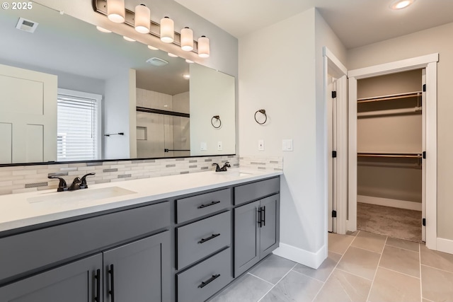 bathroom featuring vanity, an enclosed shower, tile patterned flooring, and decorative backsplash