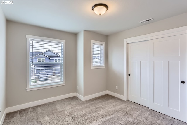 unfurnished bedroom with light carpet and a closet