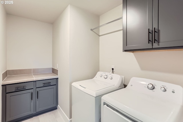 clothes washing area with cabinets and independent washer and dryer