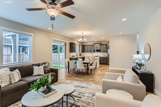 living room featuring ceiling fan with notable chandelier, sink, and light hardwood / wood-style floors