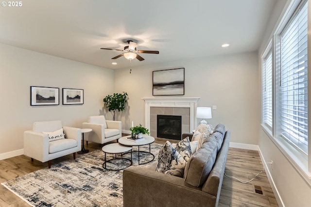 living room featuring ceiling fan, a fireplace, and light hardwood / wood-style floors