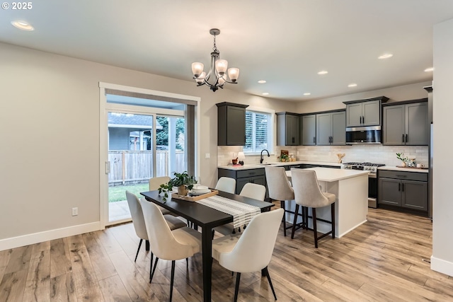 dining space featuring an inviting chandelier, sink, and light wood-type flooring