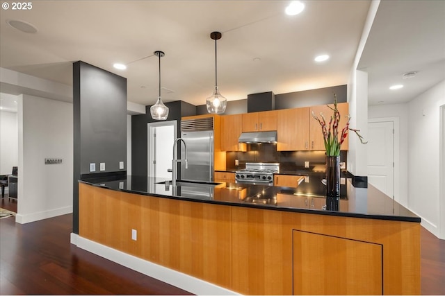 kitchen featuring dark wood-type flooring, hanging light fixtures, kitchen peninsula, stainless steel appliances, and backsplash