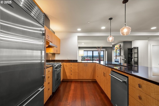 kitchen with dark wood-type flooring, sink, decorative light fixtures, high quality appliances, and kitchen peninsula