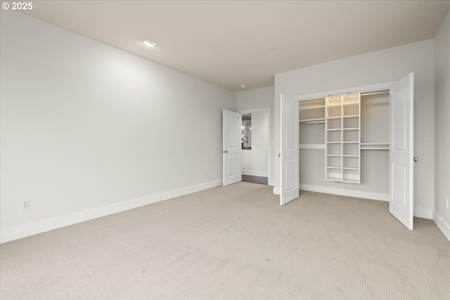 unfurnished bedroom with light colored carpet and a closet