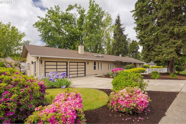 single story home featuring a chimney, driveway, and a garage