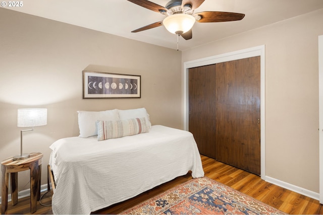 bedroom with wood finished floors, a closet, ceiling fan, and baseboards