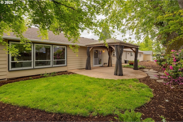 rear view of house featuring a patio area, a gazebo, a yard, and a shingled roof