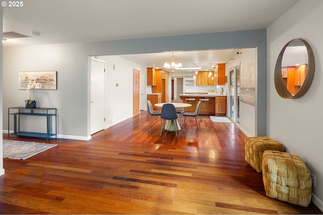 dining area with dark wood-style floors, a chandelier, and baseboards