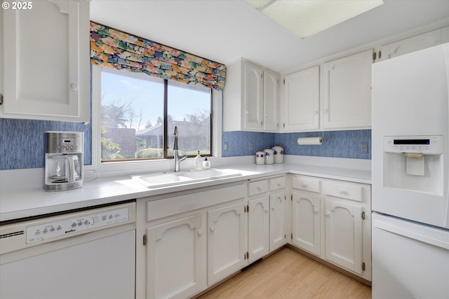 kitchen with light wood-type flooring, a sink, white appliances, white cabinets, and light countertops