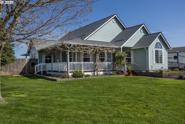 view of front of home with fence, a porch, roof with shingles, and a front yard