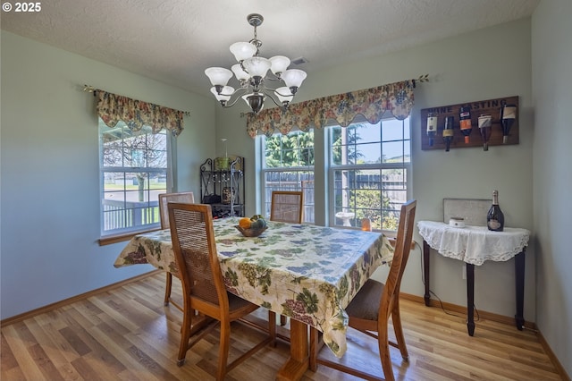 788 SE Meadows Loop, Sheridan, OR 97378 - dining area with light wood-style flooring, baseboards, an inviting chandelier, and a textured ceiling