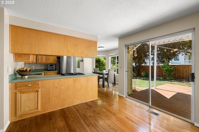 5877 NW 181st Ave, Portland, OR 97229 - kitchen with stainless steel appliances, a peninsula, wood-type flooring, and a textured ceiling