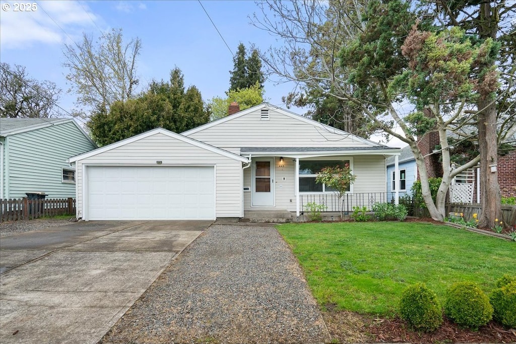view of front facade with fence, covered porch, a front yard, concrete driveway, and an attached garage
