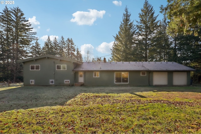 back of property featuring a garage and a yard