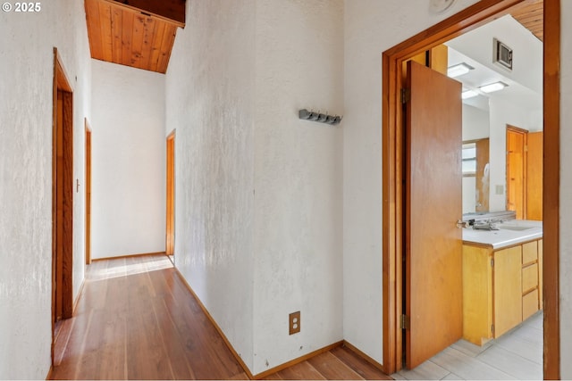 corridor featuring wooden ceiling, lofted ceiling, sink, and light wood-type flooring