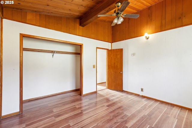 unfurnished bedroom with vaulted ceiling with beams, wooden ceiling, a closet, hardwood / wood-style flooring, and ceiling fan