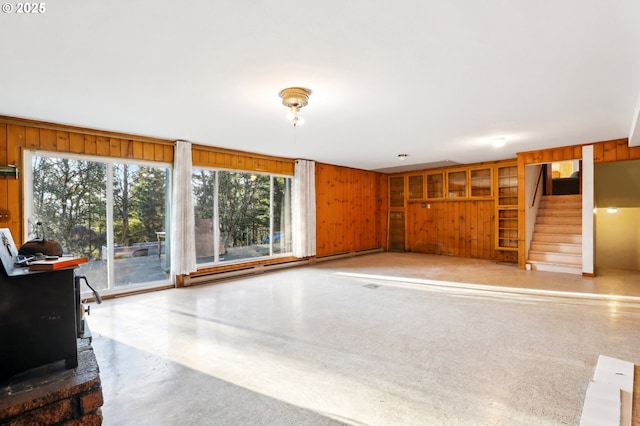 unfurnished living room featuring wooden walls and a wood stove