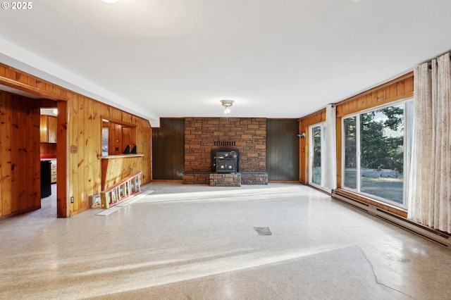 unfurnished living room featuring wooden walls and a wood stove