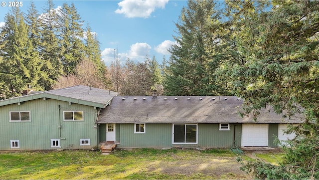 rear view of property with a garage and a yard