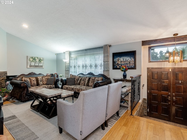 living room featuring a chandelier, vaulted ceiling, a textured ceiling, and hardwood / wood-style flooring