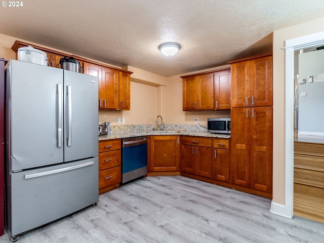 kitchen featuring a textured ceiling, stainless steel appliances, light hardwood / wood-style flooring, and sink