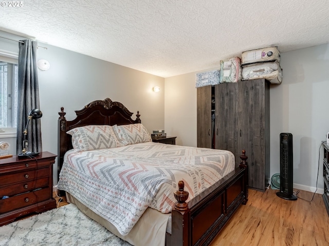 bedroom with a textured ceiling and light hardwood / wood-style floors