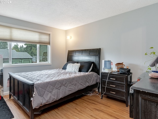 bedroom featuring a textured ceiling and light hardwood / wood-style flooring