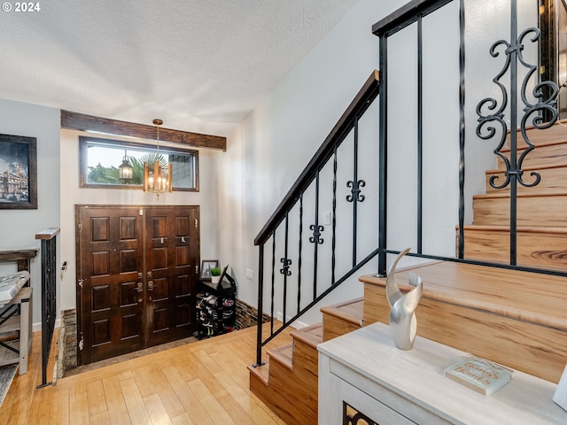 foyer entrance featuring an inviting chandelier, a textured ceiling, and light hardwood / wood-style floors