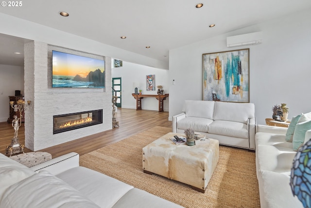 living area with recessed lighting, a large fireplace, wood finished floors, baseboards, and a wall mounted AC