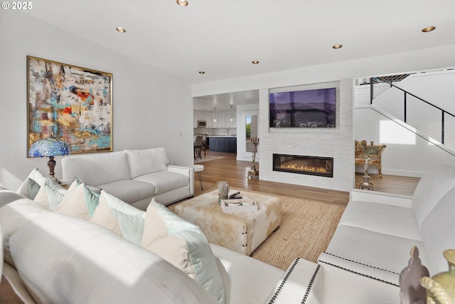 living area with a large fireplace, wood finished floors, and recessed lighting