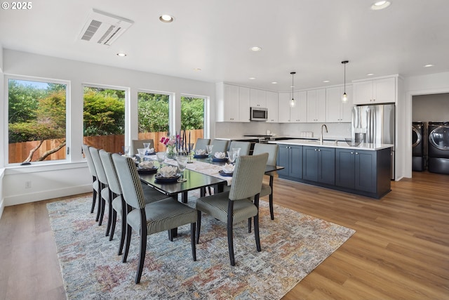 dining space with baseboards, light wood finished floors, recessed lighting, and washer and dryer