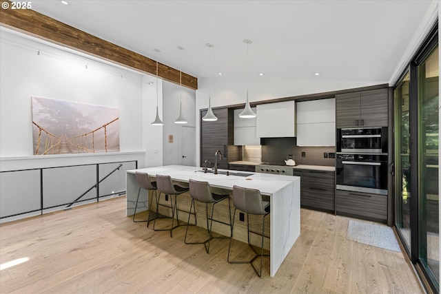 1801 NW Walmer Dr, Portland, OR 97229 - kitchen featuring modern cabinets, light wood-type flooring, a kitchen breakfast bar, a kitchen island with sink, and recessed lighting
